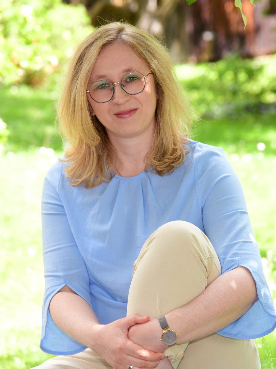 Miriam Althaler sitzt im Garten, die Arme um ein Knie gelegt, und lächelt in die Kamera