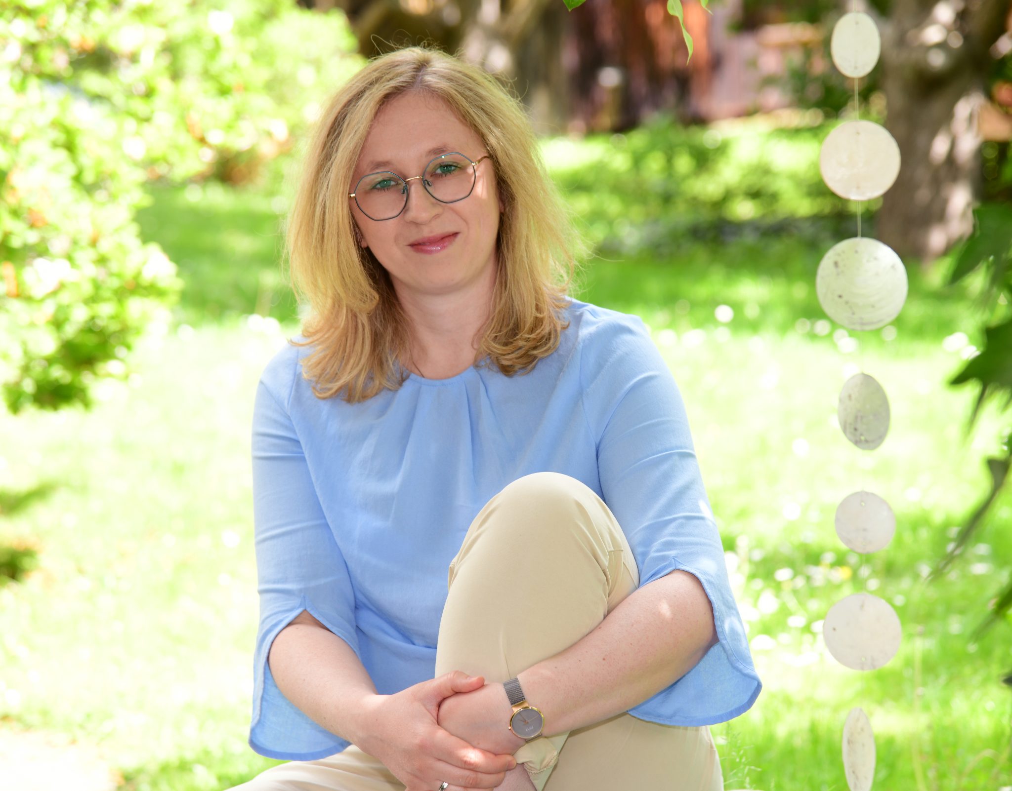 Miriam Althaler sitzt im Garten und lächelt in die Kamera
